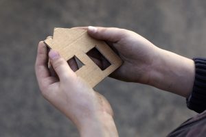 homeless boy holding a cardboard house, dirty hand